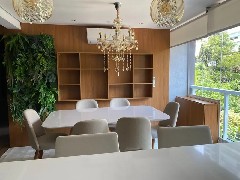 Sala de jantar com lustre de cristal, nicho de madeira e jardim vertical