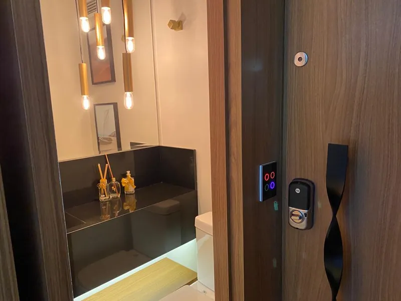 Lavabo com pendentes e bancada preta ao lado da porta de entrada com teclado touch e fechadura digital