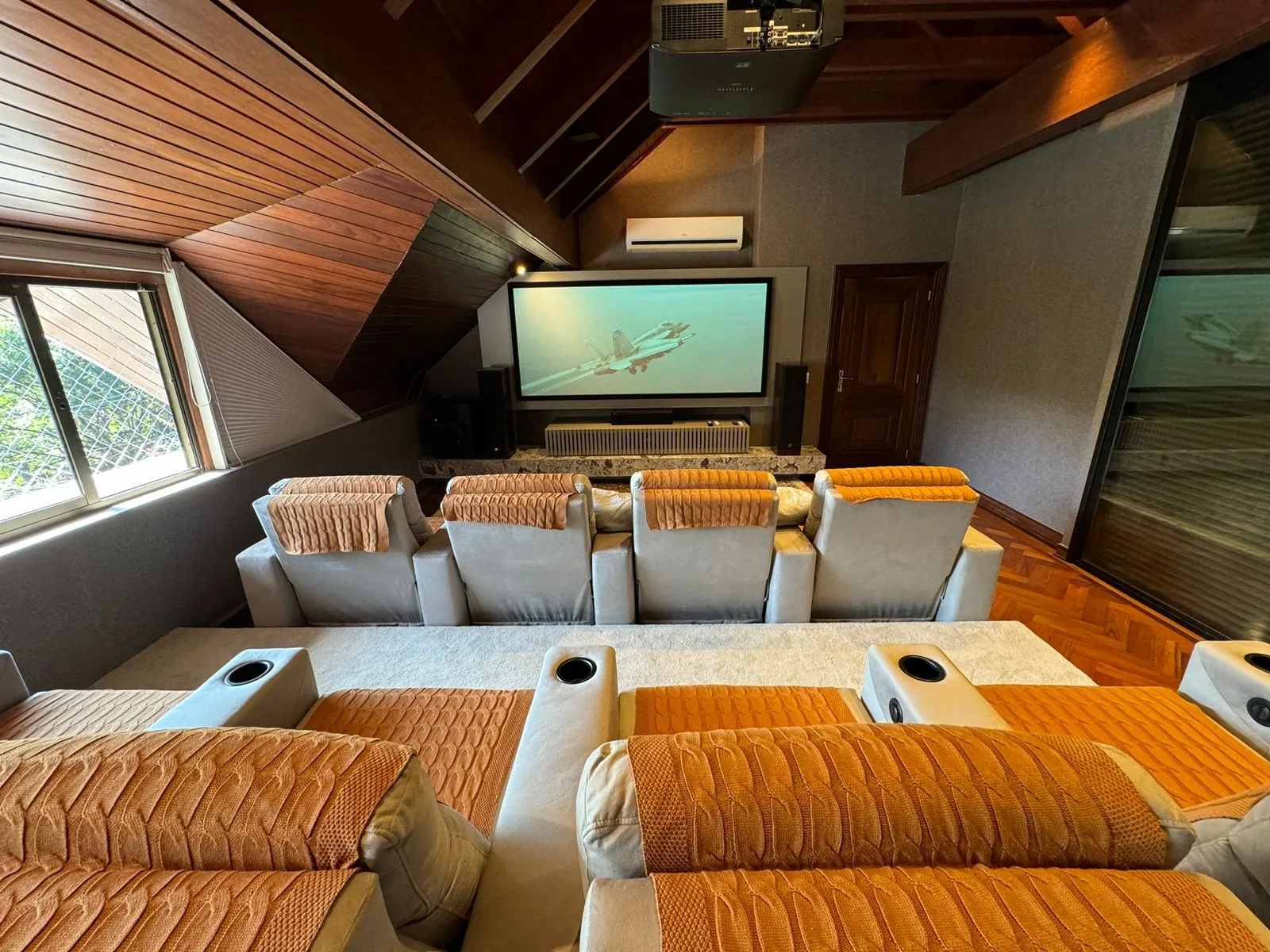 Cinema room under a wooden roof, with recliners, projector and screen