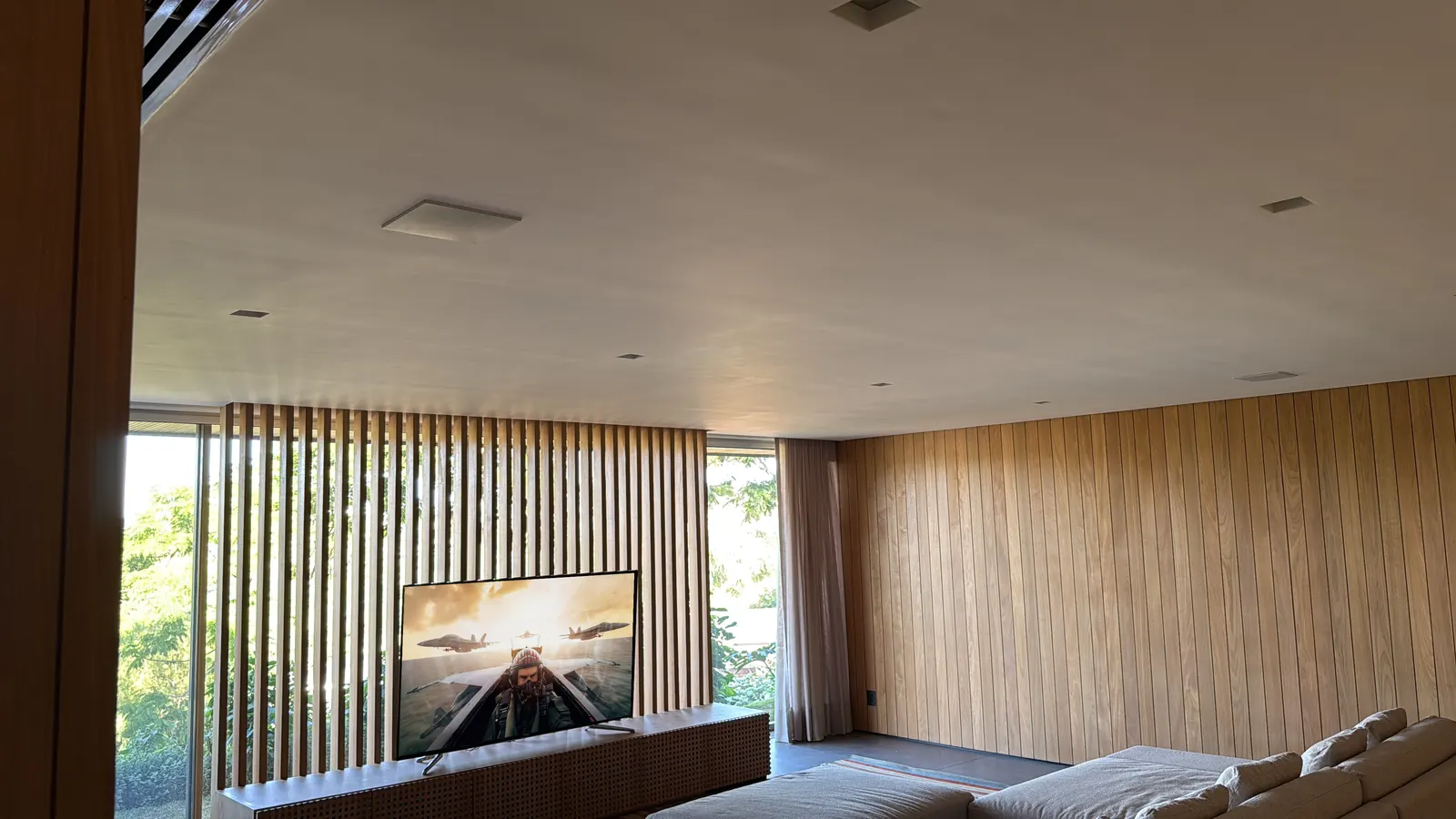 TV room with wooden louvers, TV on and a view of the garden