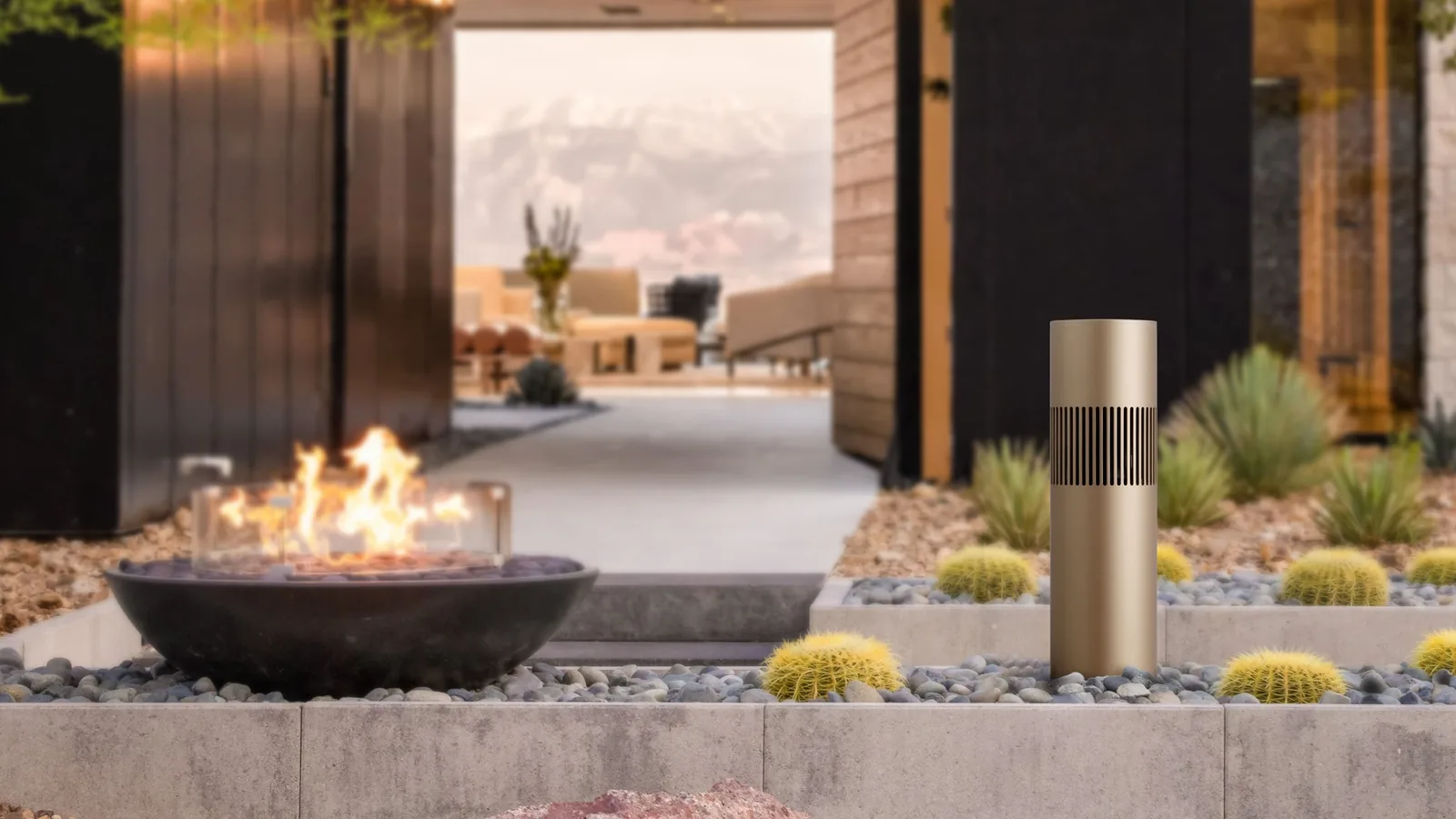Caixa Bang & Olufsen em jardim, ao lado de uma lareira externa