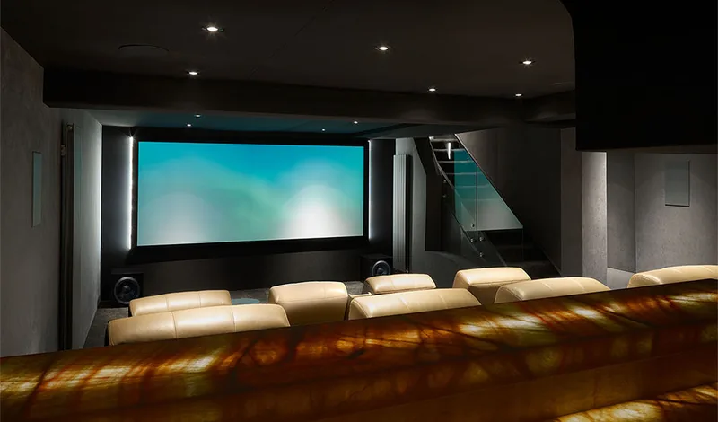 Sala de cinema com caixas Bowers & Wilkins e tela projetada