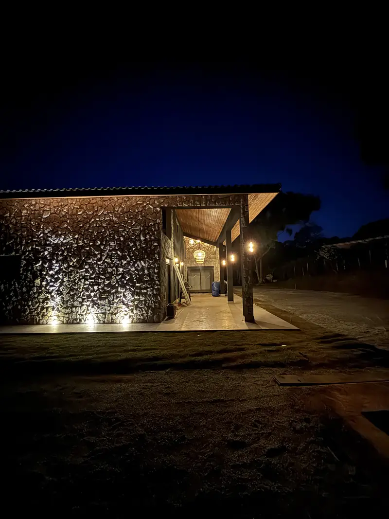 Fachada de residência à noite com parede de pedra iluminada