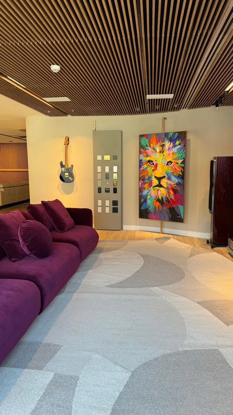 Music room with a purple sofa, a guitar on the wall and a panel with automation keypads