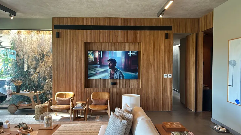Living room with a slatted wood wall, built-in TV and armchairs