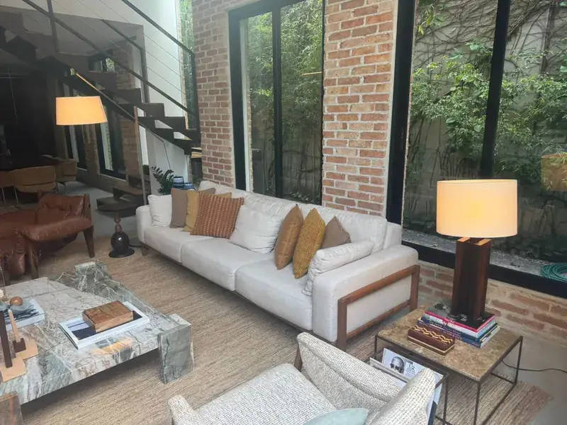 Living room with a light sofa, lamps and an exposed brick wall