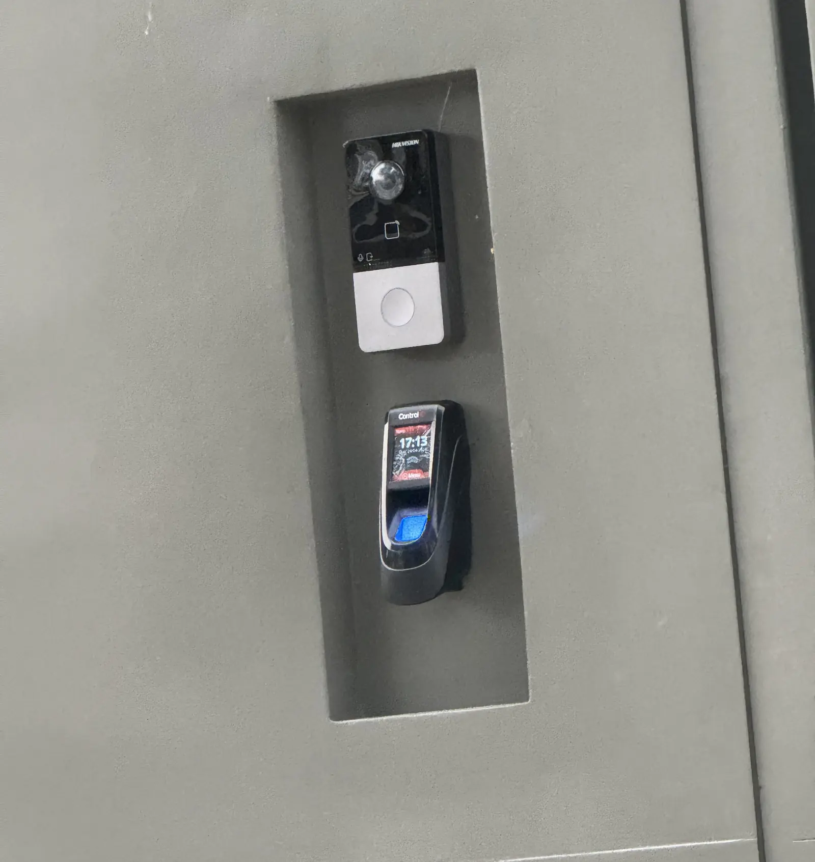 Video intercom and fingerprint reader recessed into a niche in a concrete wall