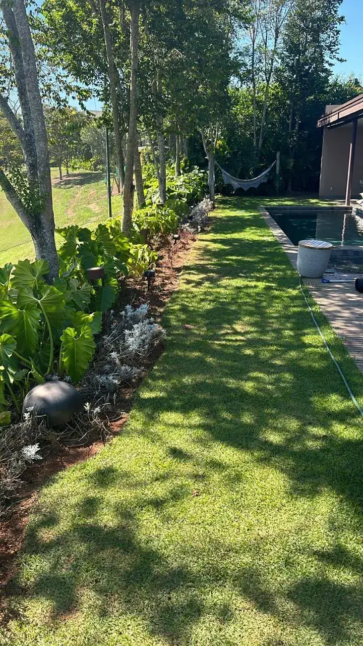 Caixa de som externa no canteiro do jardim, ao lado da piscina