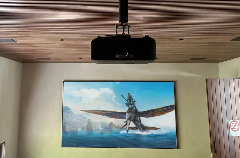 Cinema room with a projector in the wooden ceiling and a movie on the screen