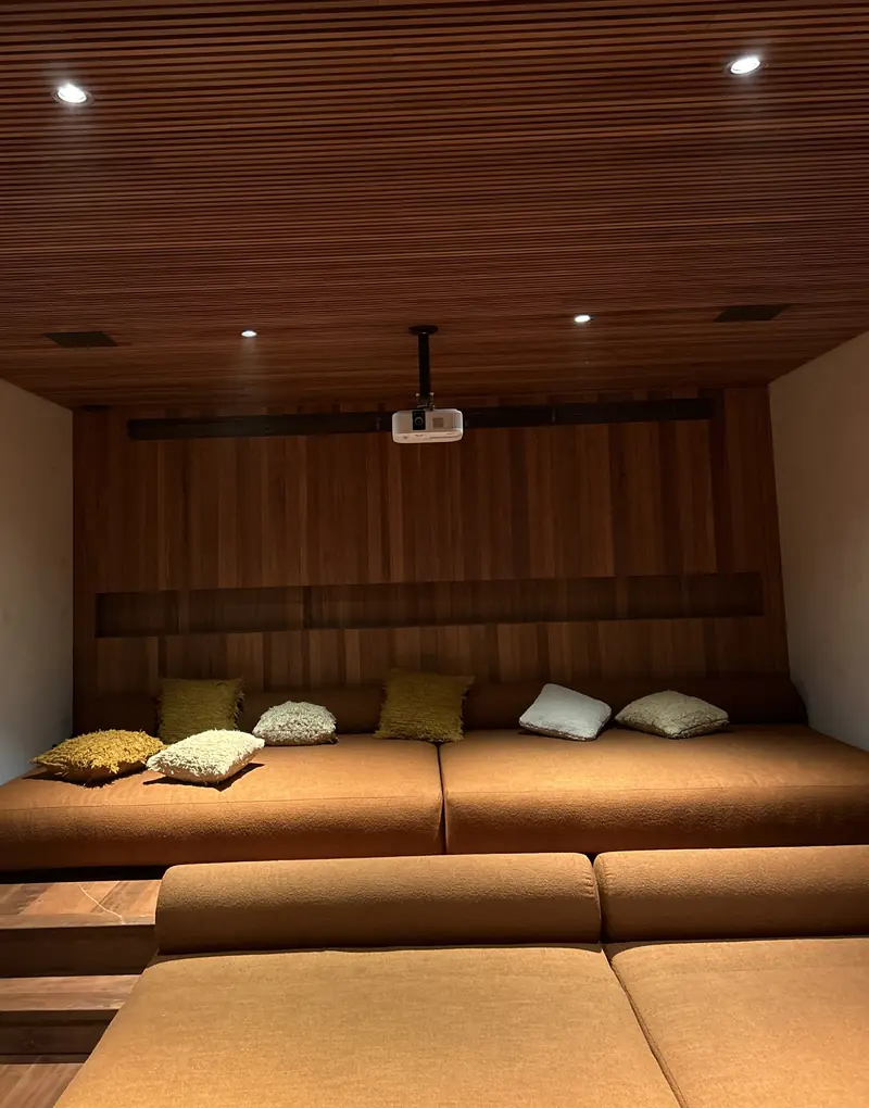 Sala de cinema com sofás em degraus e forro de madeira