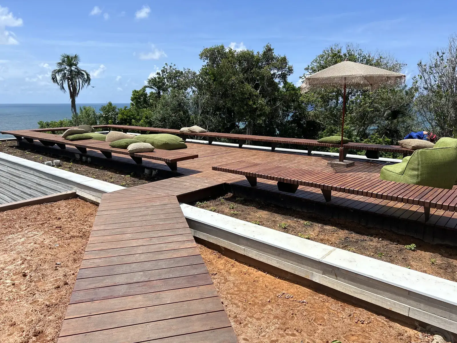 Wooden deck with cushions and a sea view at a villa in Itacaré