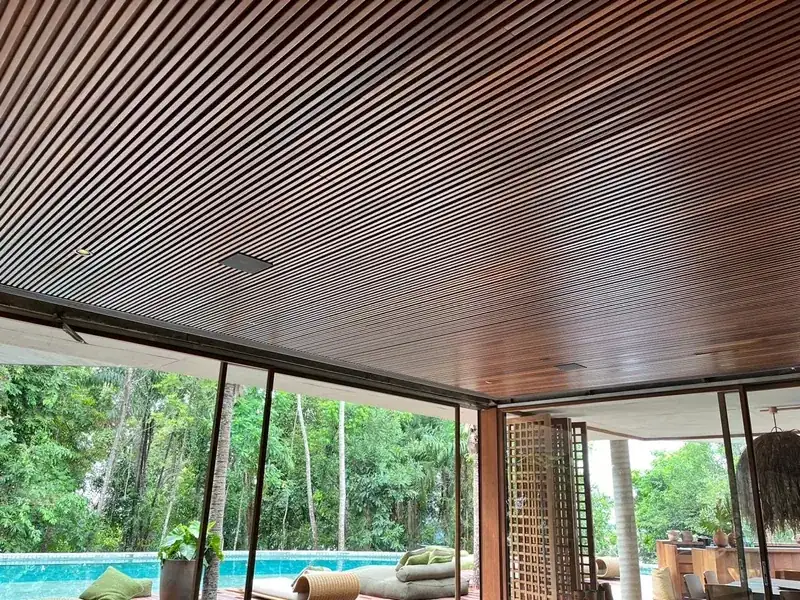Living room with a wooden ceiling, open to the pool and the forest