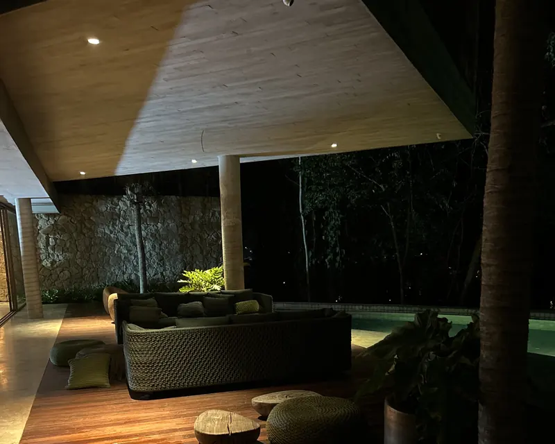 Lounge beneath the house at night, with soft lighting over the deck and pool